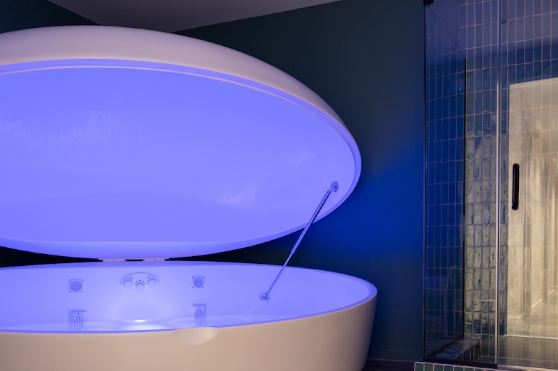 Sacred Earth — float therapy pod glowing with soft blue light